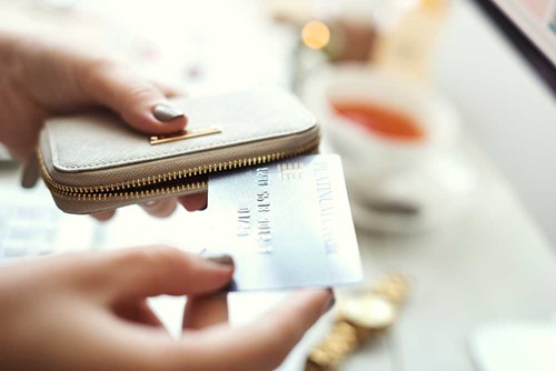 Woman removing credit card from wallet to pay