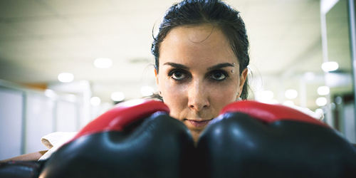 Close-up shot of woman's face, holding up boxing gloves.